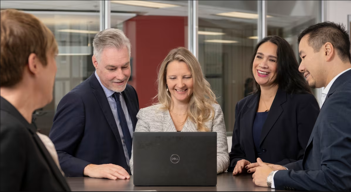 Professionals gathering around a laptop
