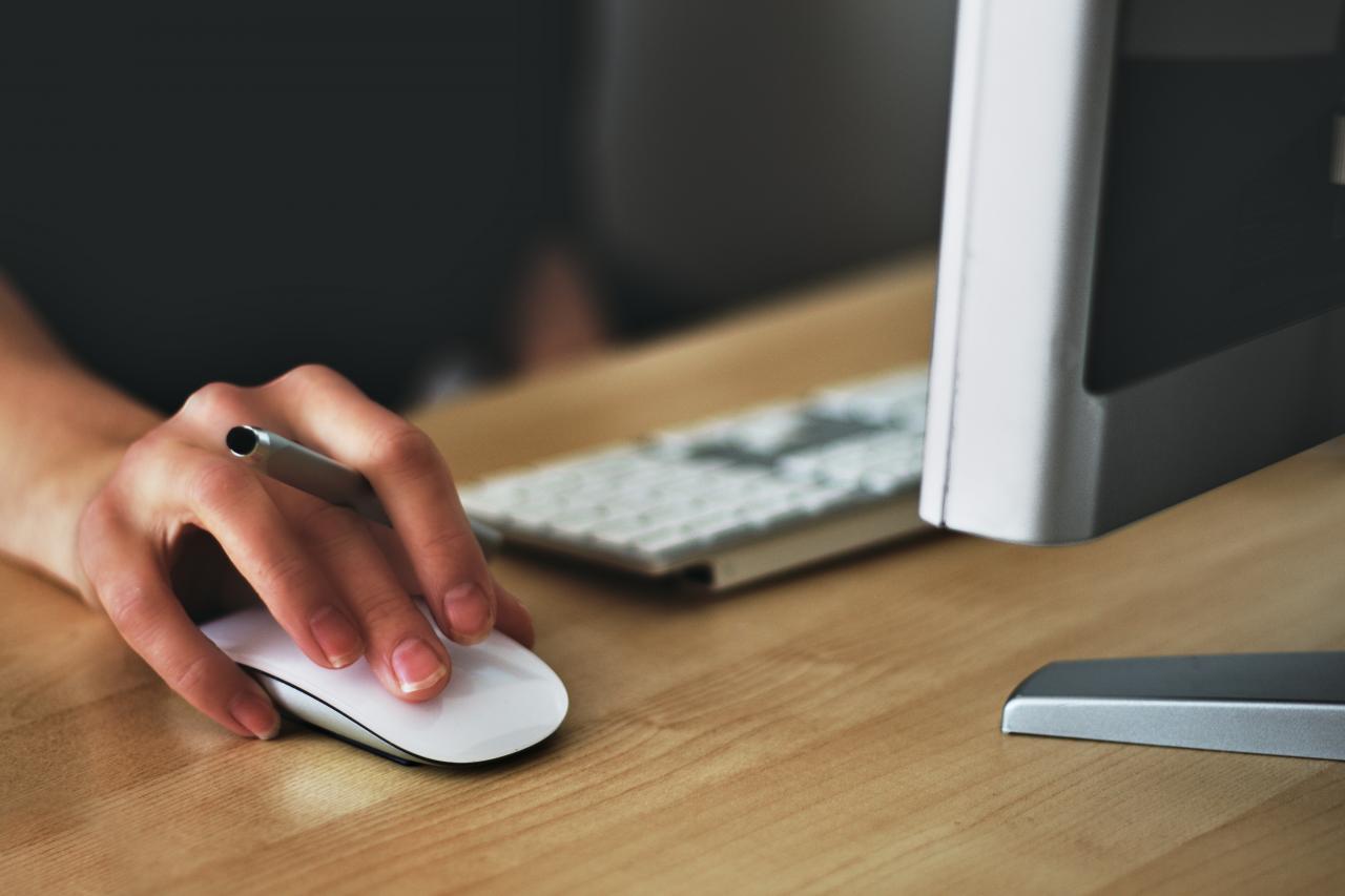 Person using computer mouse with pen between fingers 