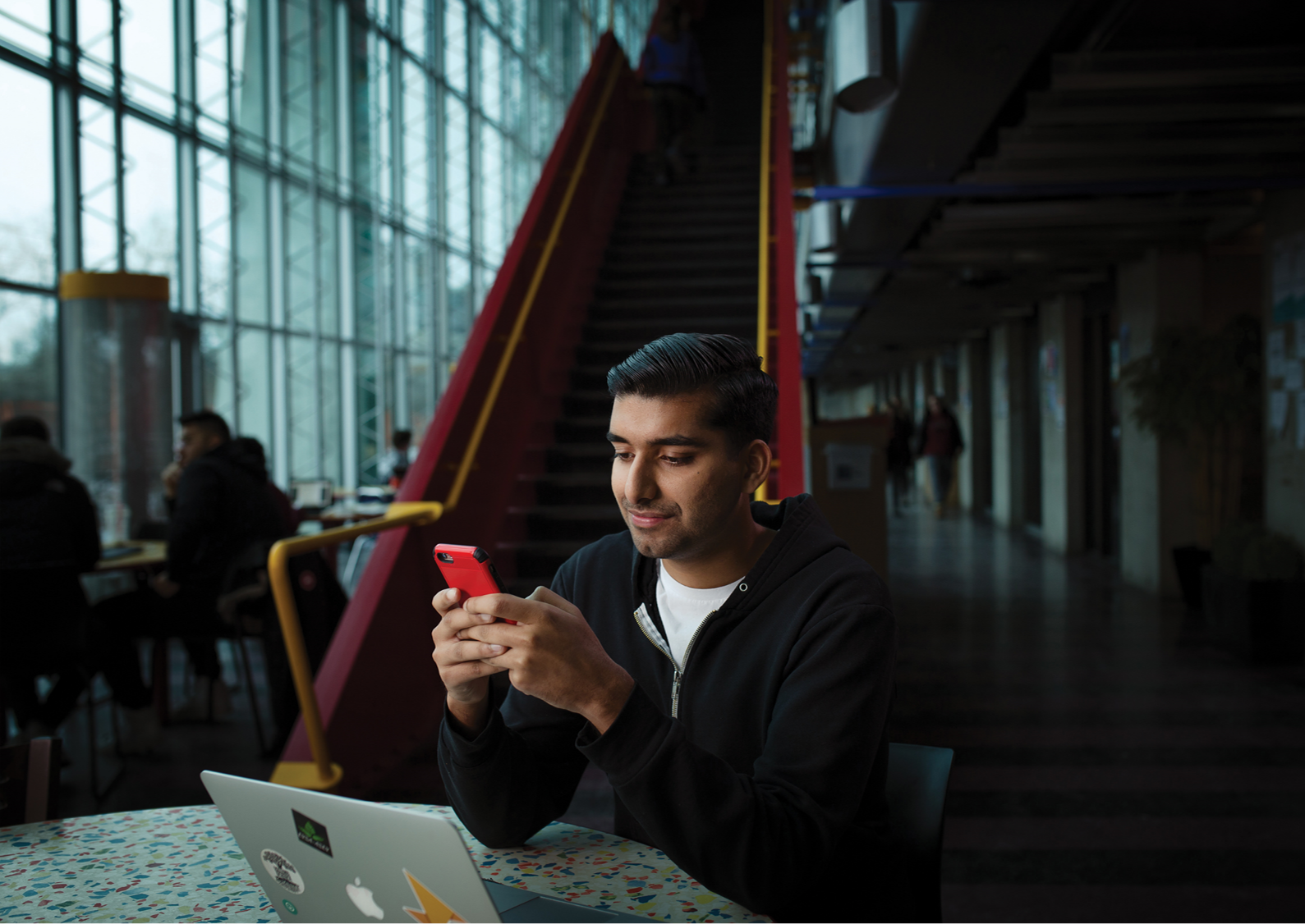 a young man looking at his phone, sitting in SITE hall