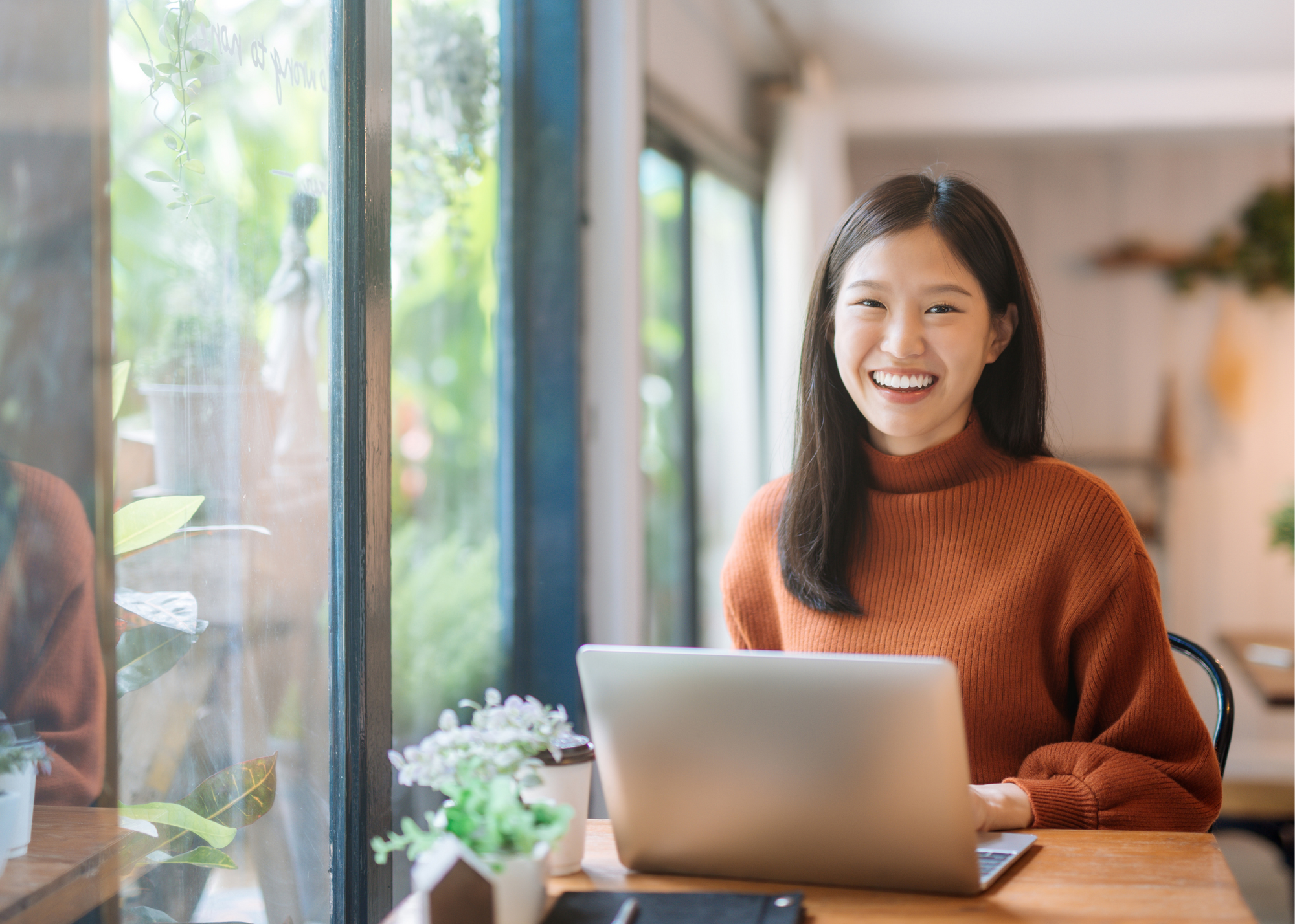 Smiling woman in front of laptop in café