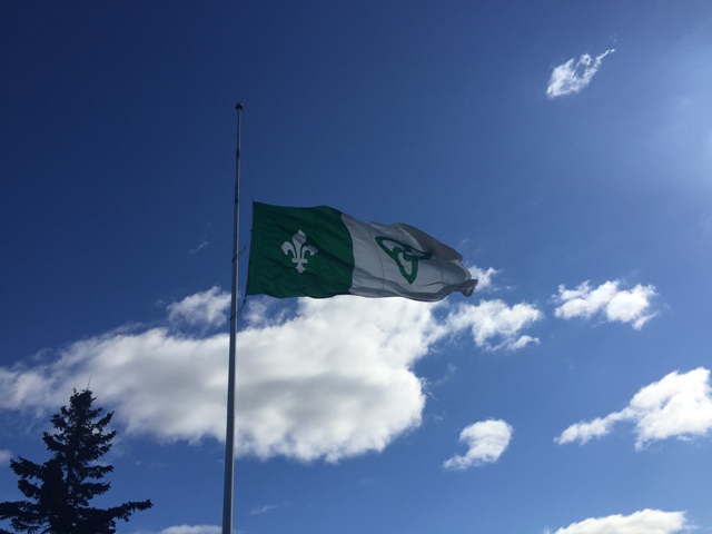 Franco-Ontarien flag waving over a blue sky.