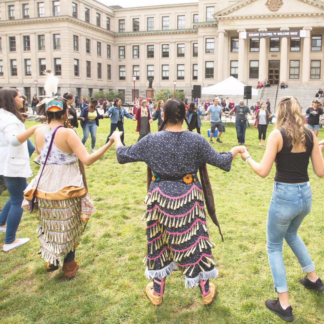 Image shows students dancing in a circle holding hands.