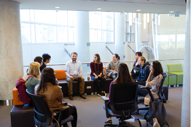 Students sitting in a circle listening to a person speaking