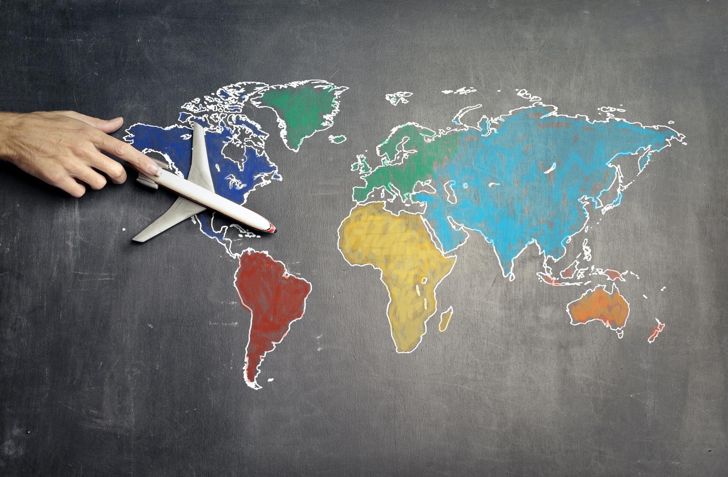 Chalk drawing of world map with plane flying over Canada.