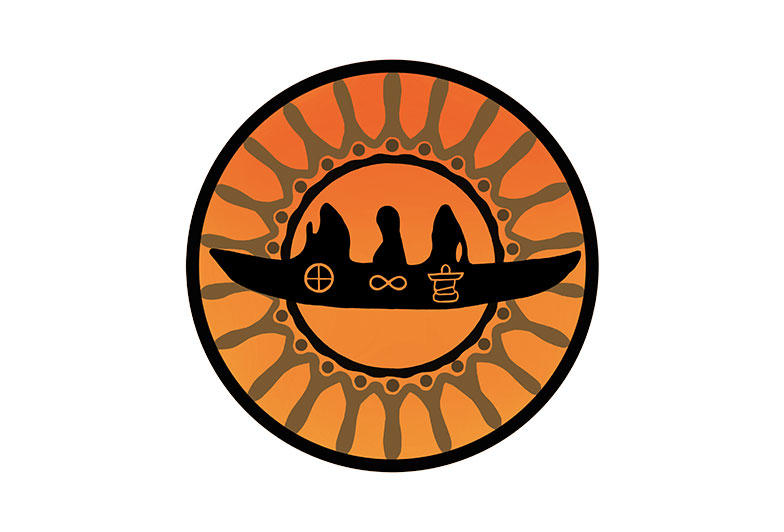 Image shows the logo for the Indigenous Students' Association, which is an orange circle that features a black canoe in the center with three figures aboard. A medicine wheel, an infinite symbol, and an inukshuk appear on the side of the canoe.
