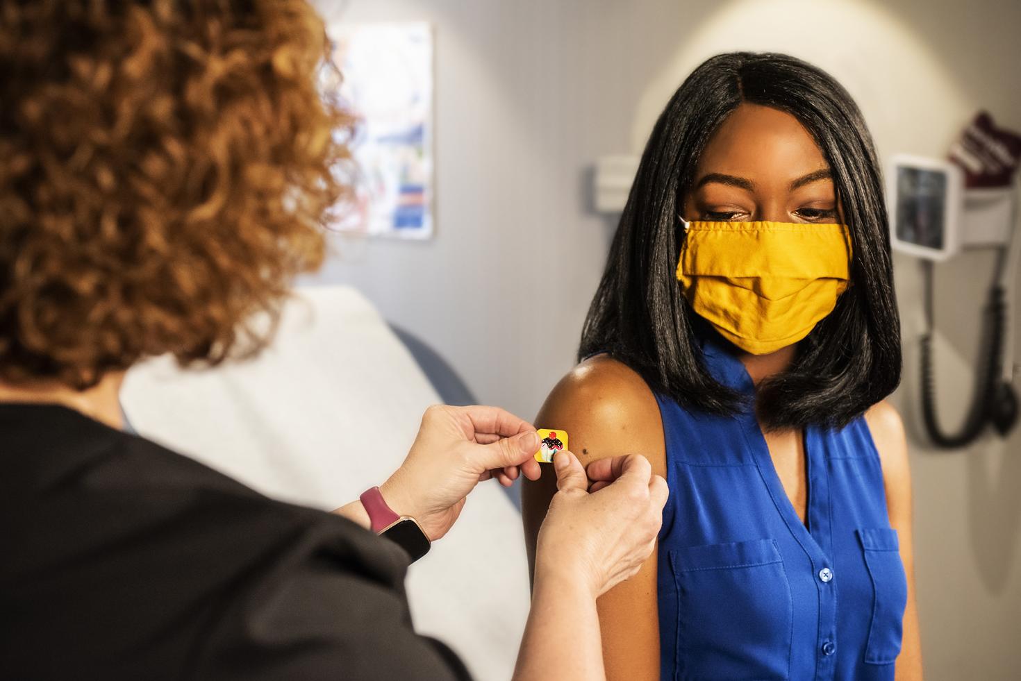 Nurse applying band-aid on a woman after getting a vaccine