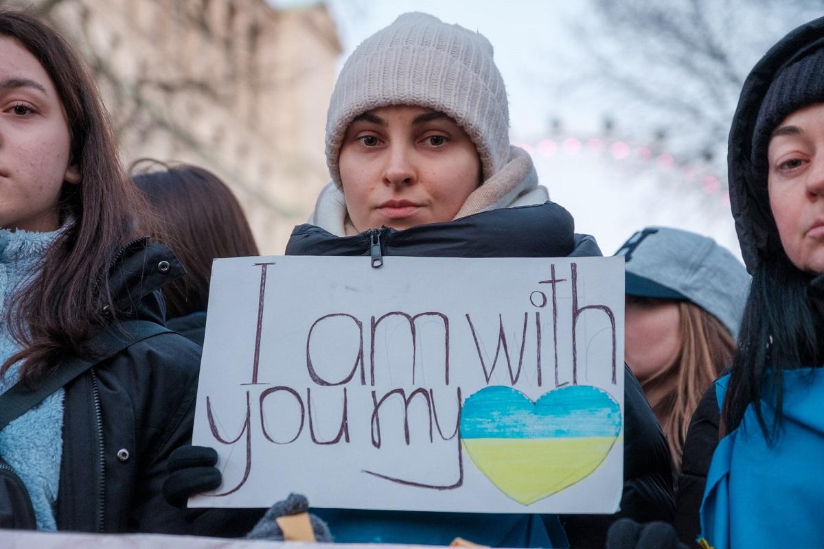 Woman among group of women holding sign reading 'I am with you my Ukraine'