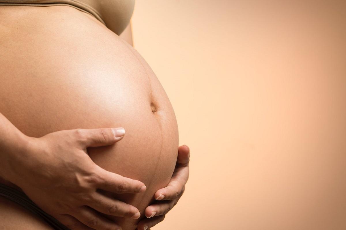 Pregnant belly cradled by mother's own hands