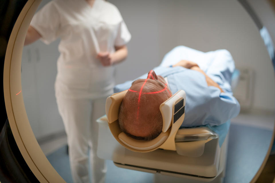 Laser covers bald man's cranium as he is put into CT scan