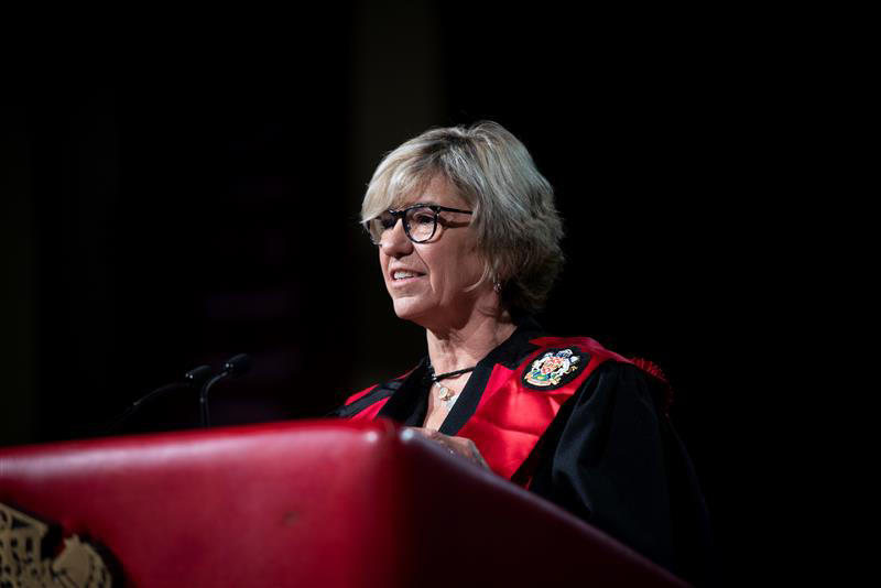 Woman at podium wearing graduating robe - onorary Doctorate recipient Julia Elvidge 