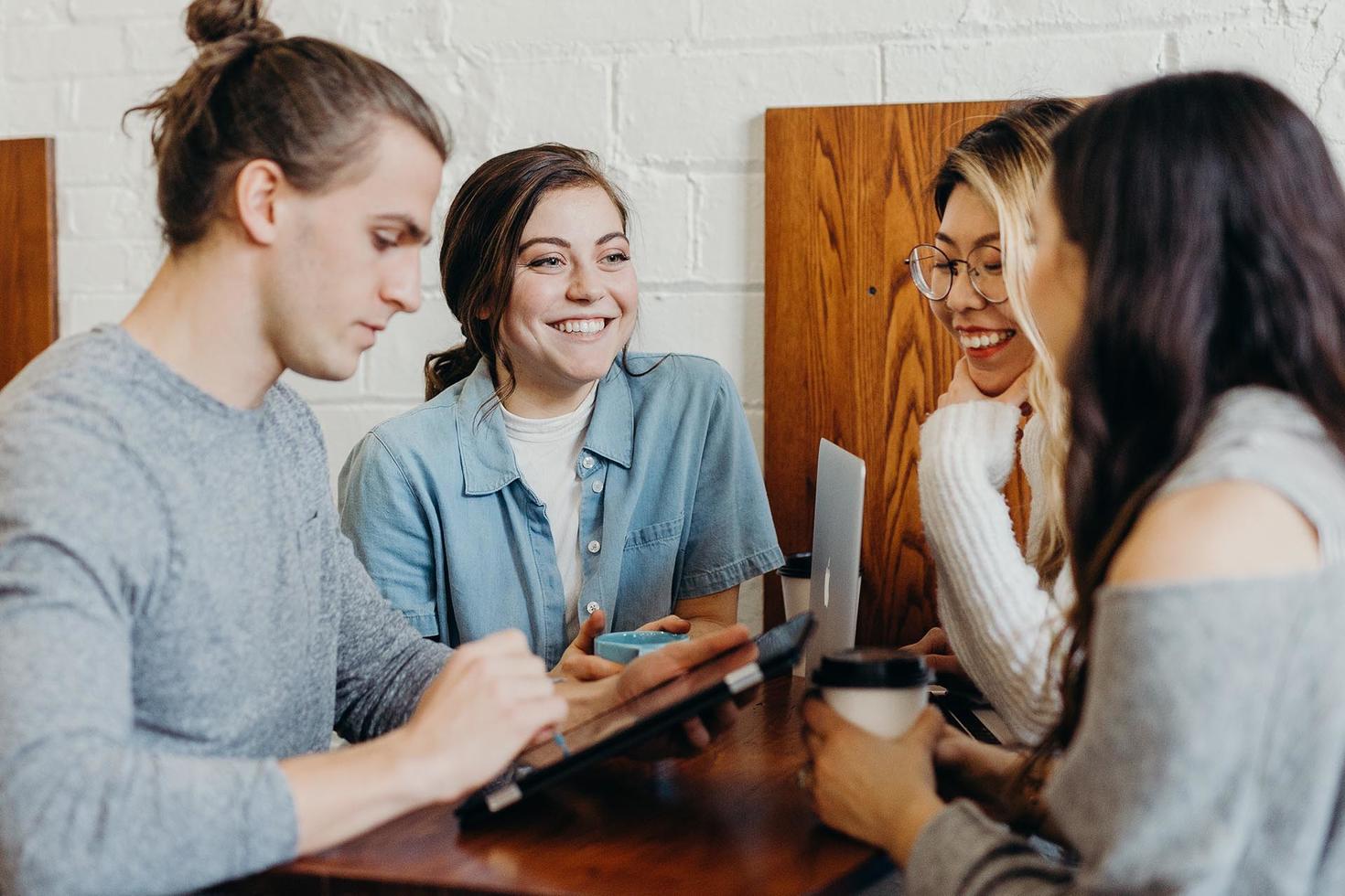 Four students practicing language skills around laptop