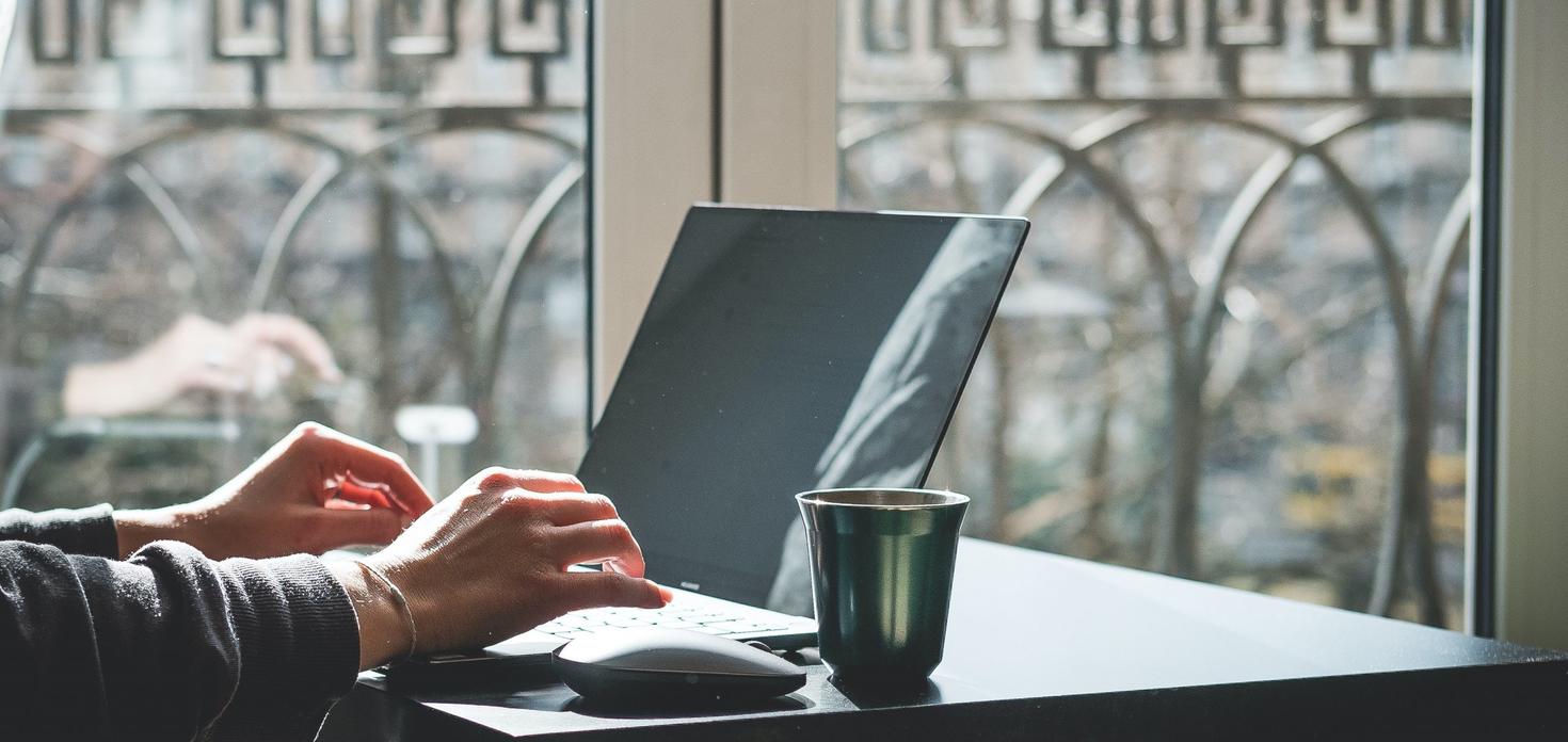 Person at the computer with a coffee cup.
