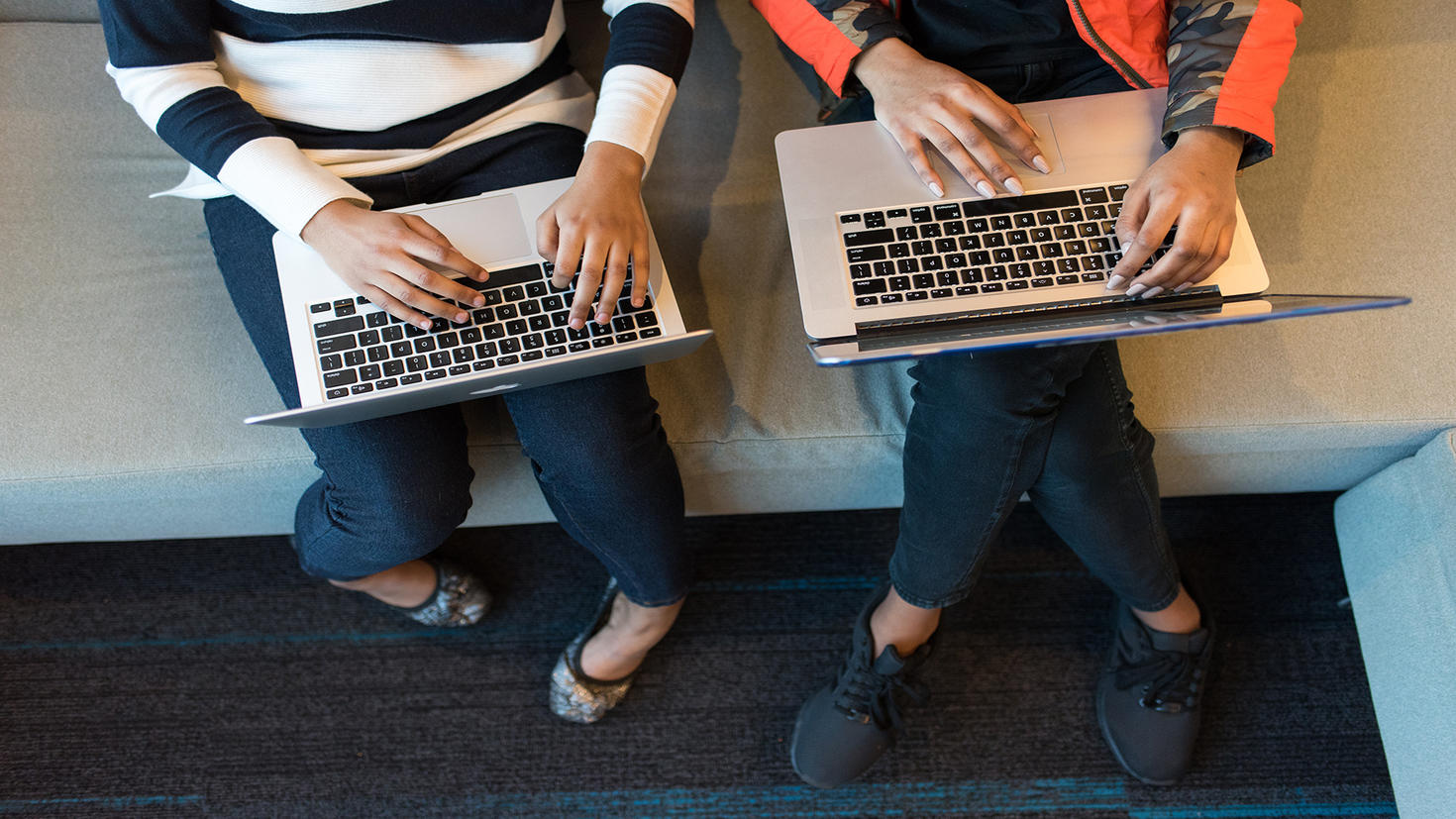 Two people typing on laptops