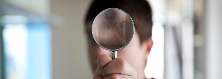 Man looking through magnifying glass