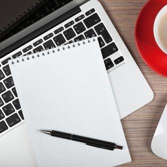 paper pad and pen on a laptop