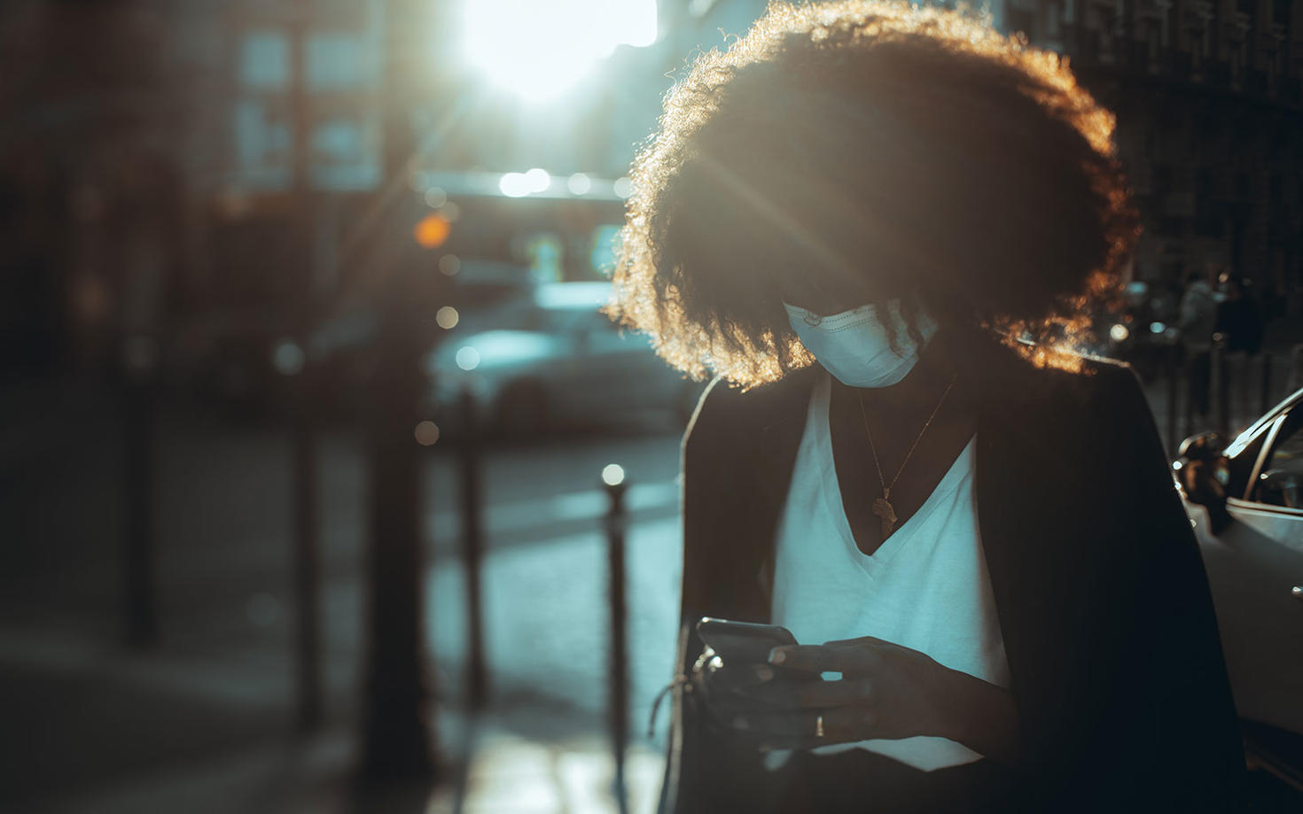 A woman looking at her phone while wearing a mask.