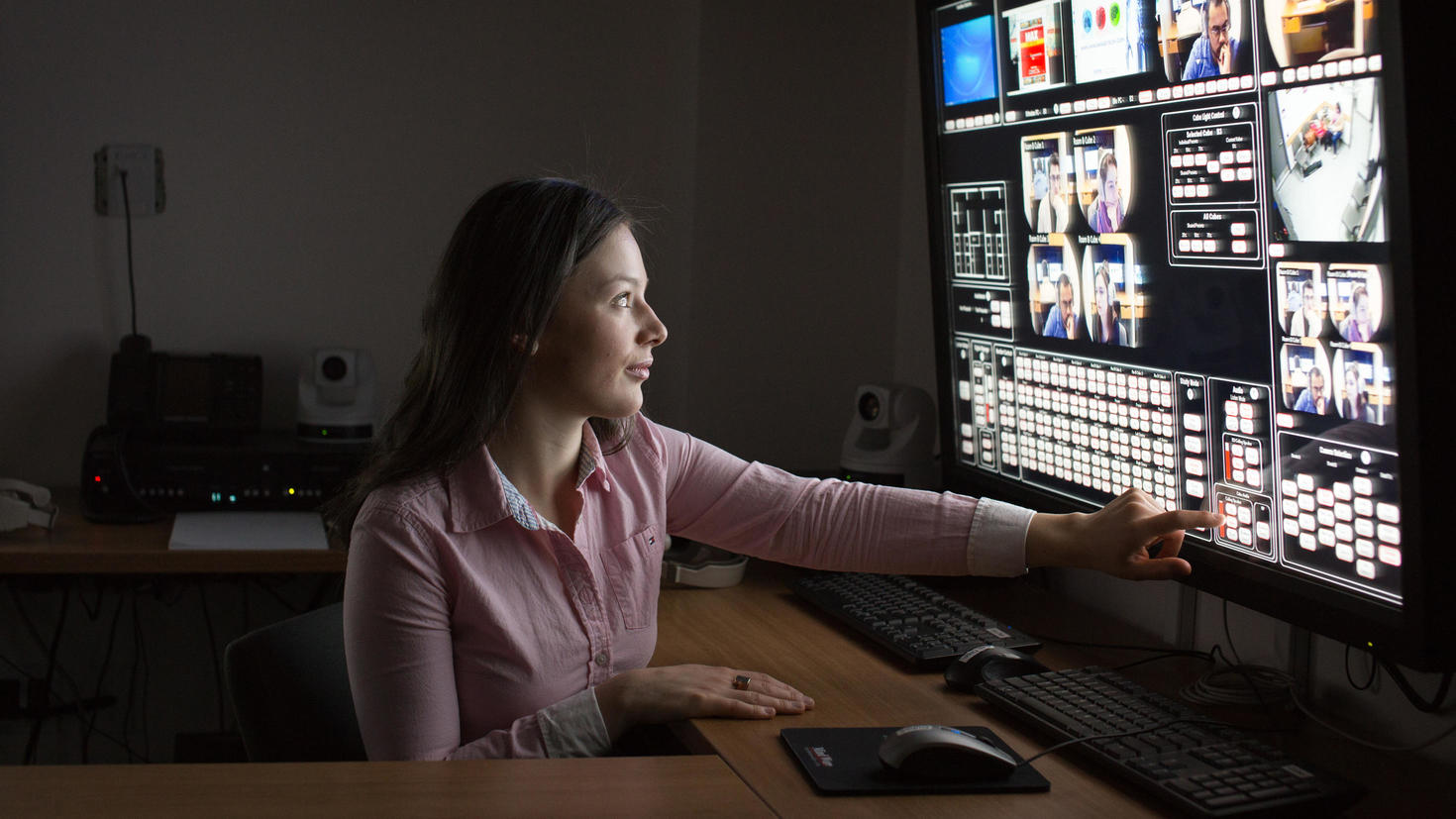 Woman touching one of several screens in dark lab