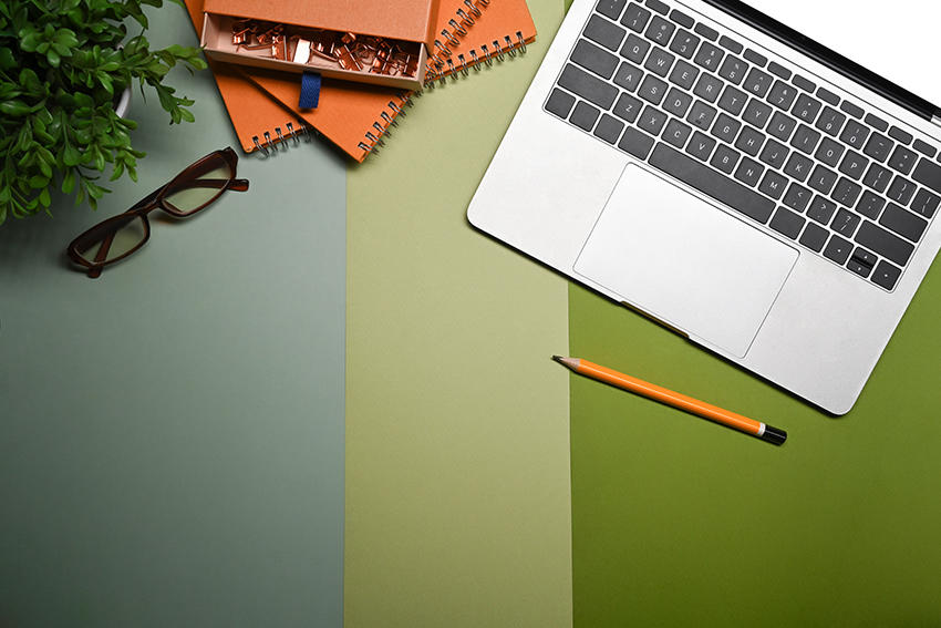 Laptop surrounded by glasses and pencil 