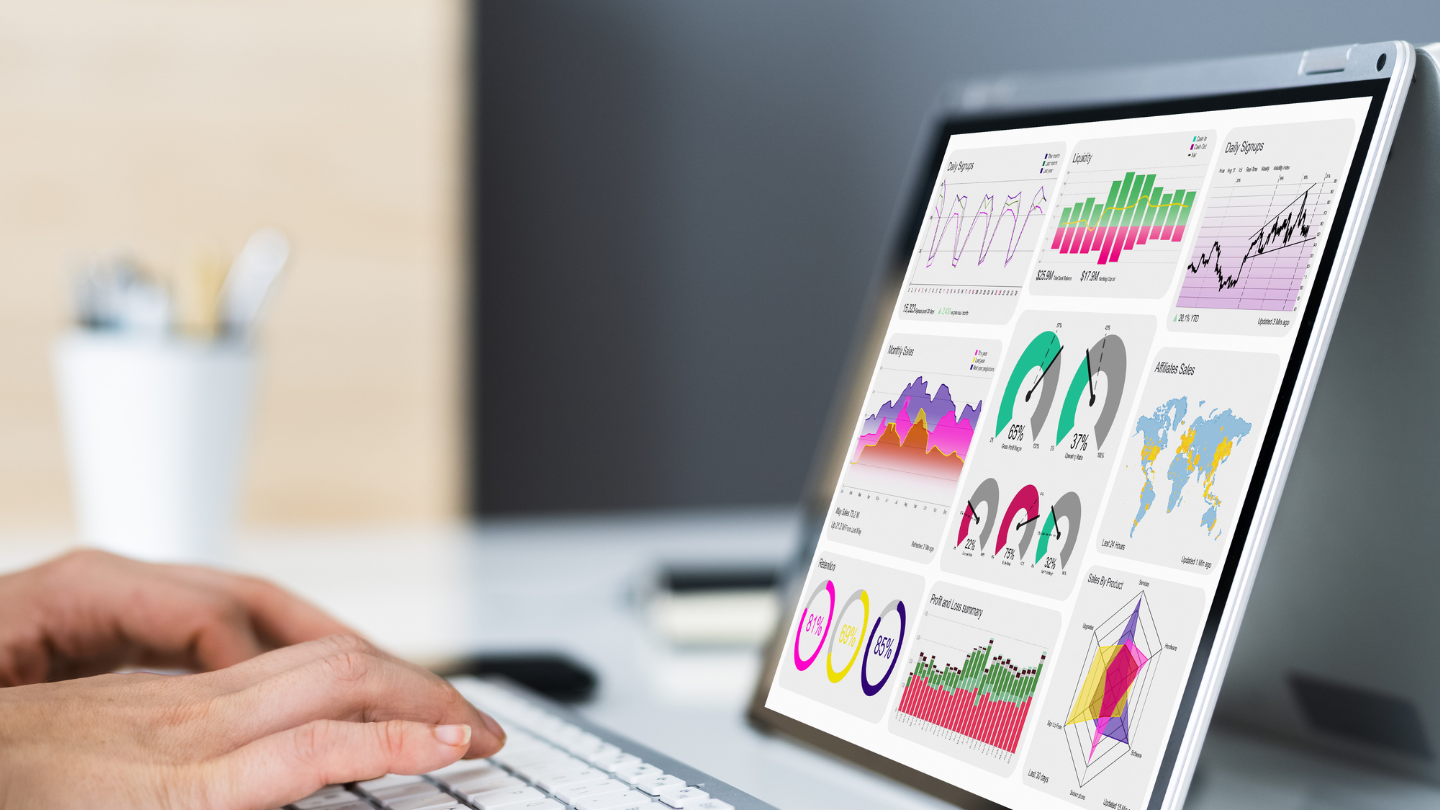 hands typing on a laptop keyboard, laptop displaying charts symbolizing data