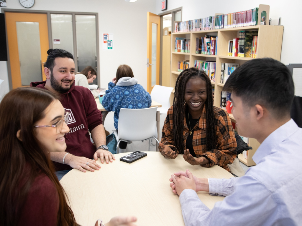 	Students sitting together at a table and laughing at the Julien-Couture Resource Centr