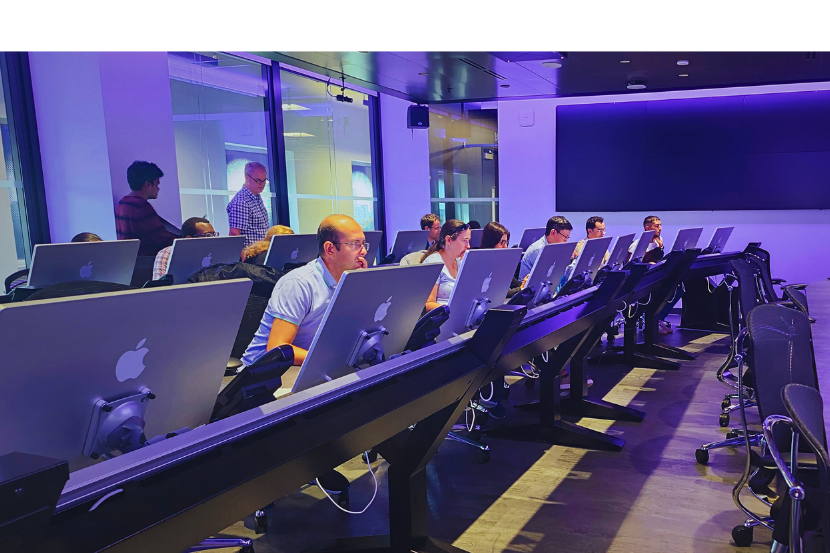 two rows of diverse people working on computers in a computer lab environment