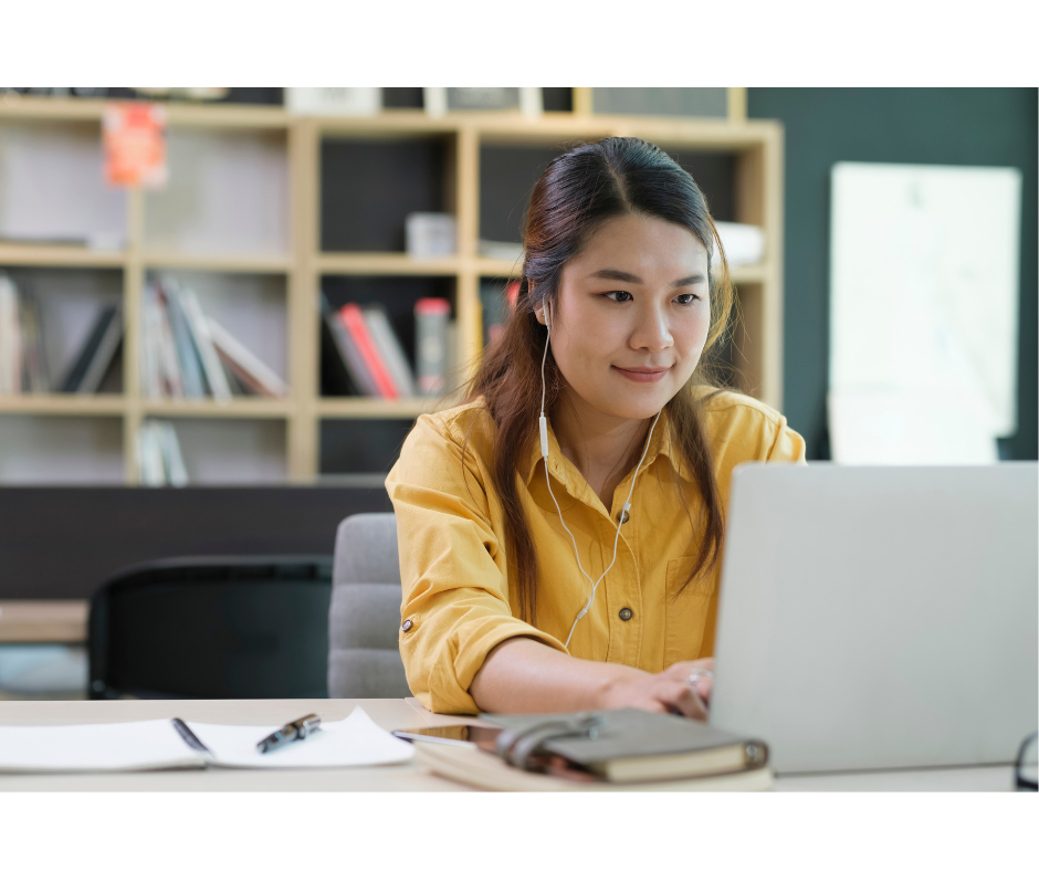 Young professor with yellow shirt in front of computer, smiling attentively