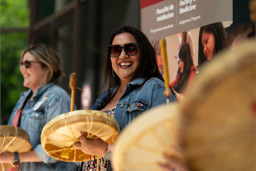 Two people smiling and beating drums