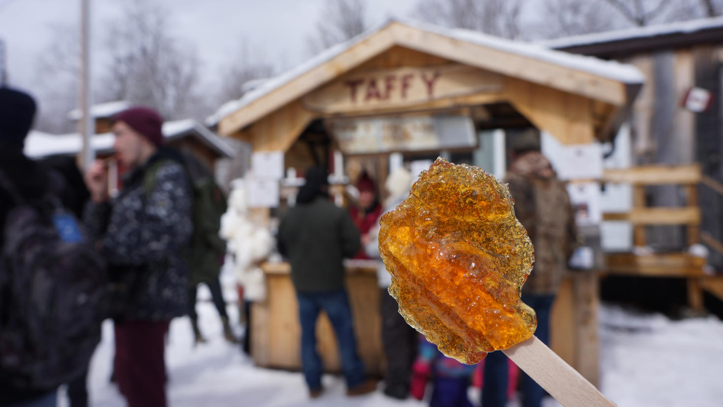 Popsicle stick with maple on it with people in the background