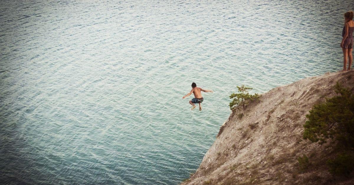 Man jumping off a cliff into a body of water