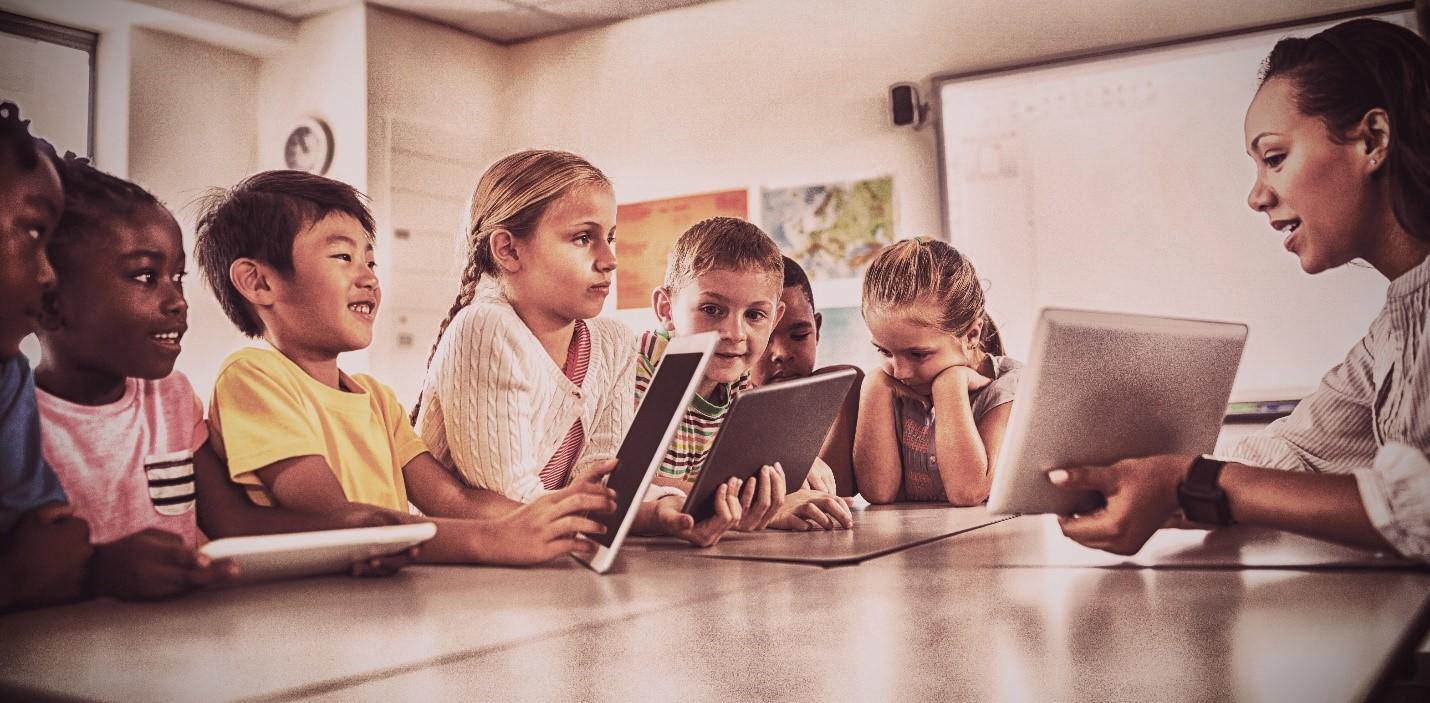 Teacher holding a tablet in front of students with tablets in their hands