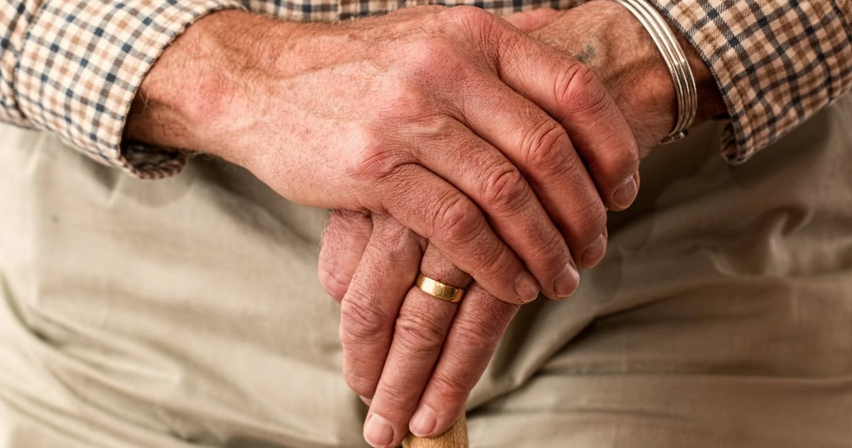 Seniors' hands crossed on a cane