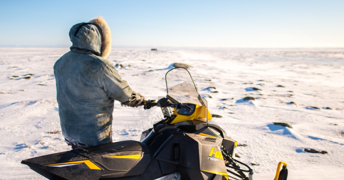 An Inuit standing next to his snowmobile in the Arctic