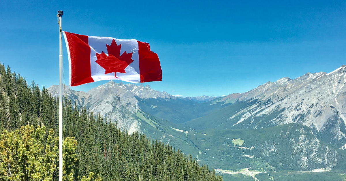 Canada flag in front of mountains.