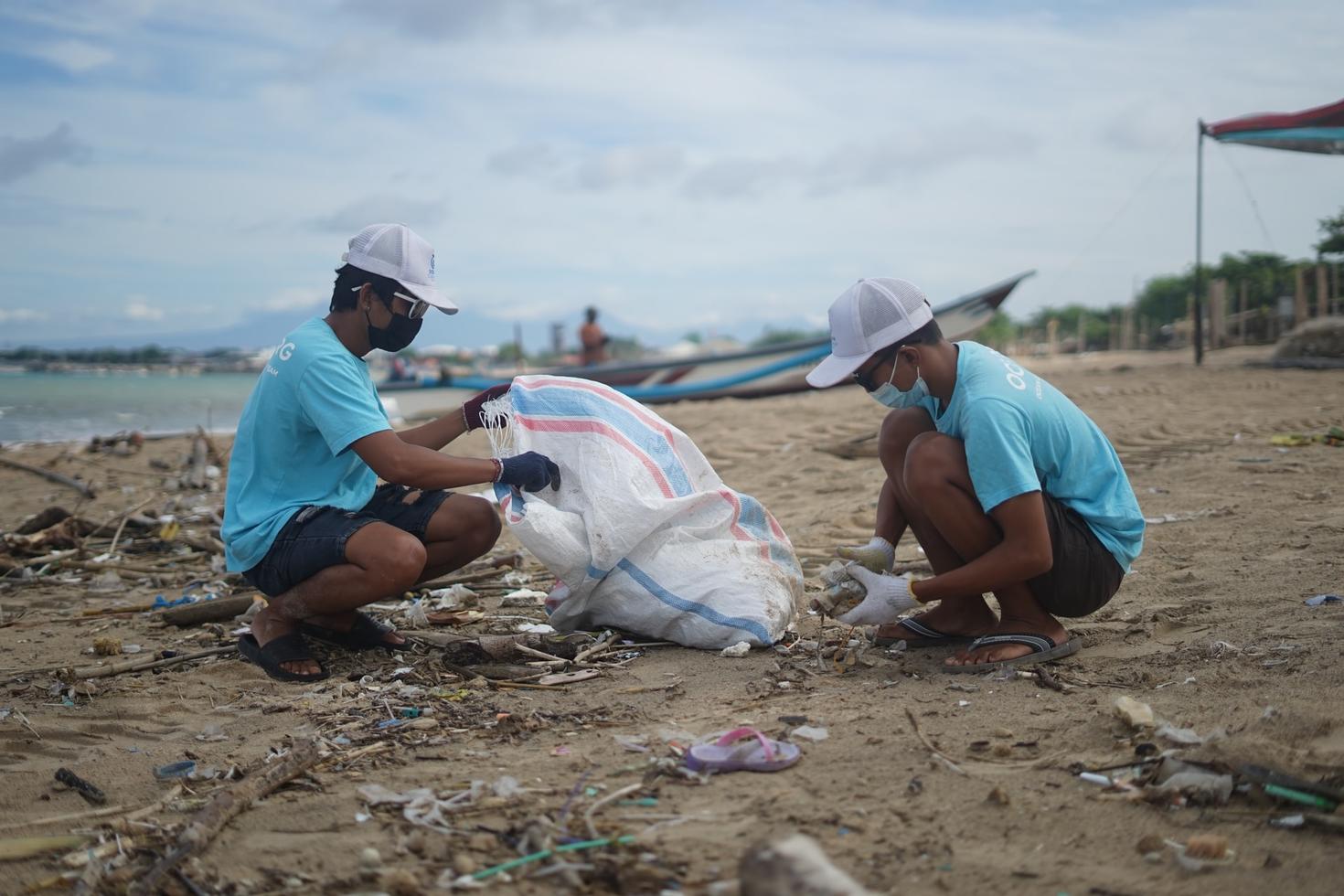 Pair of workers clean garbage off a beach