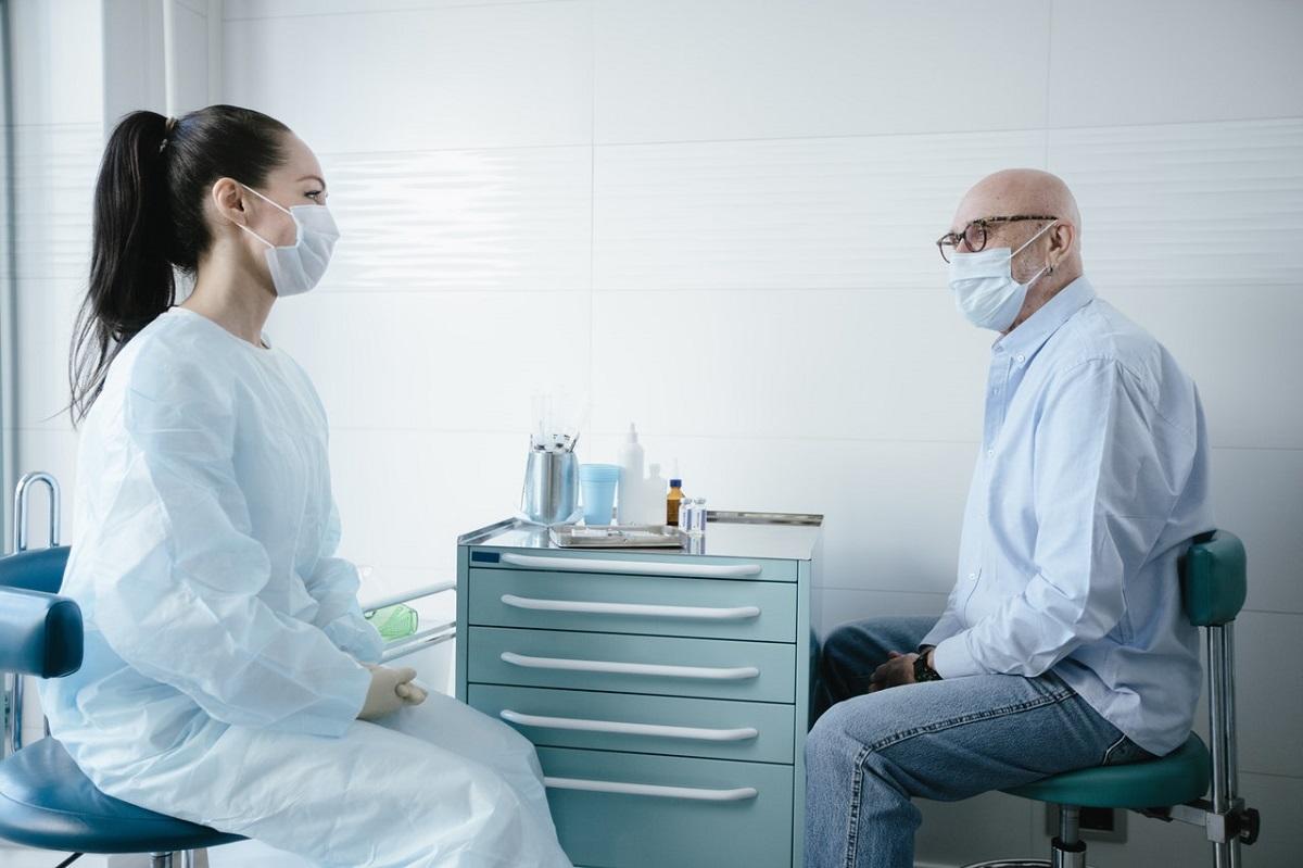 Doctor speaking with patient, both wearing masks