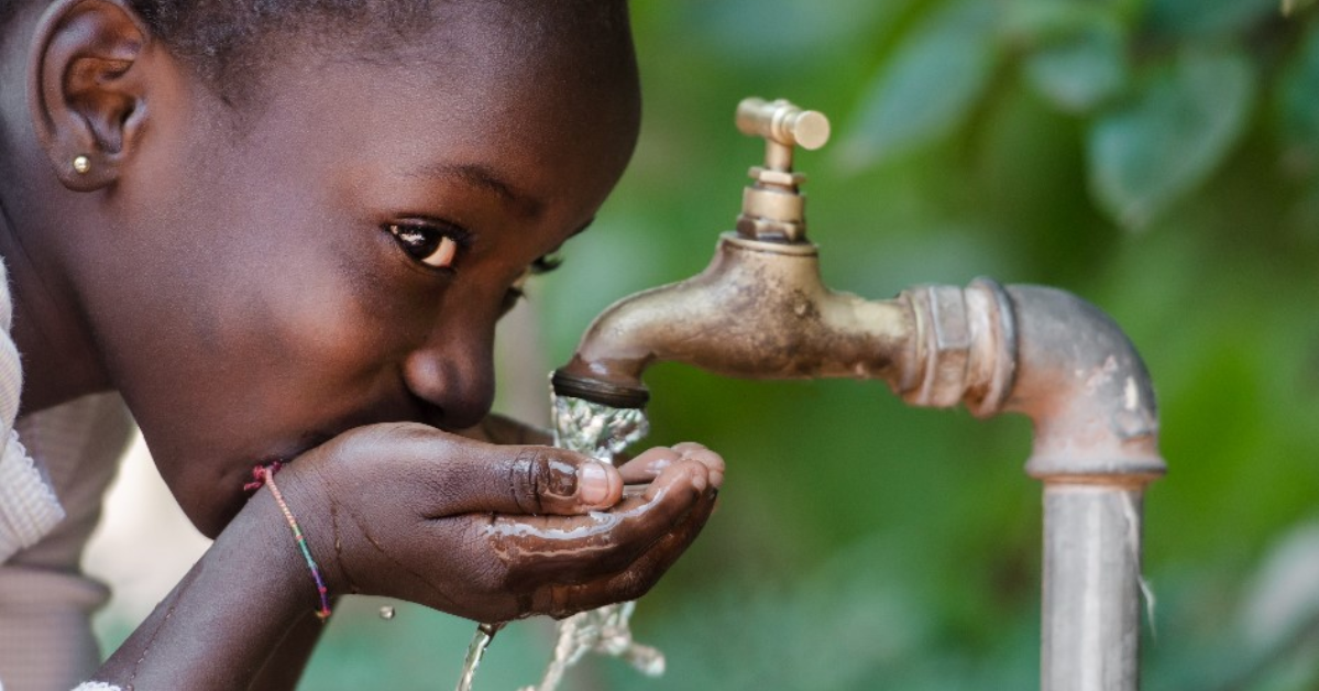 A child drinking water out of a faucet