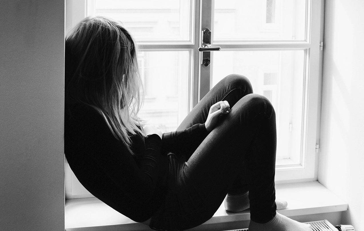 Black and white picture of teenage girl sitting in front of window