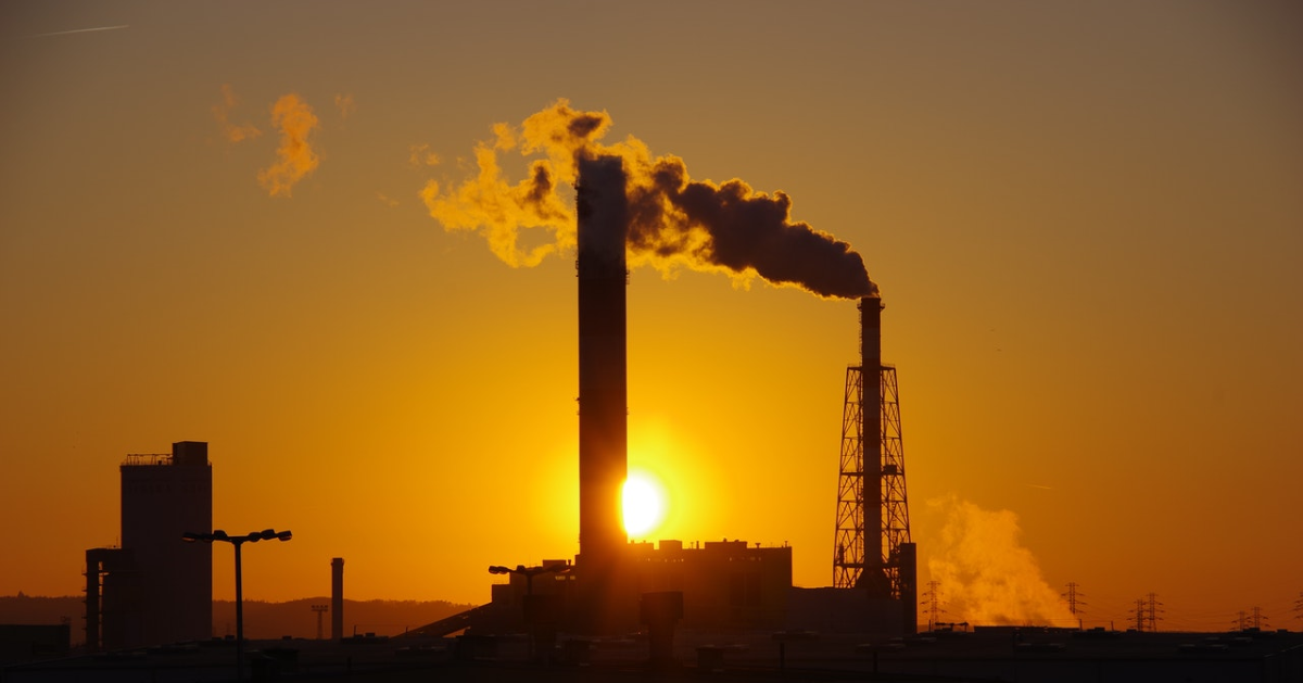 Smoke coming out of a chimney, with the sun in the background