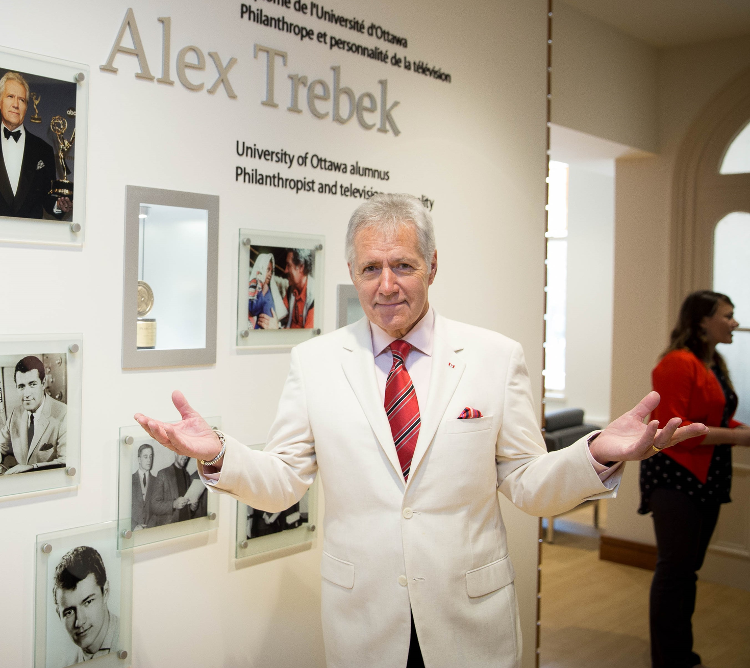 Alex Trebek standing in front of wall dedicated to him.