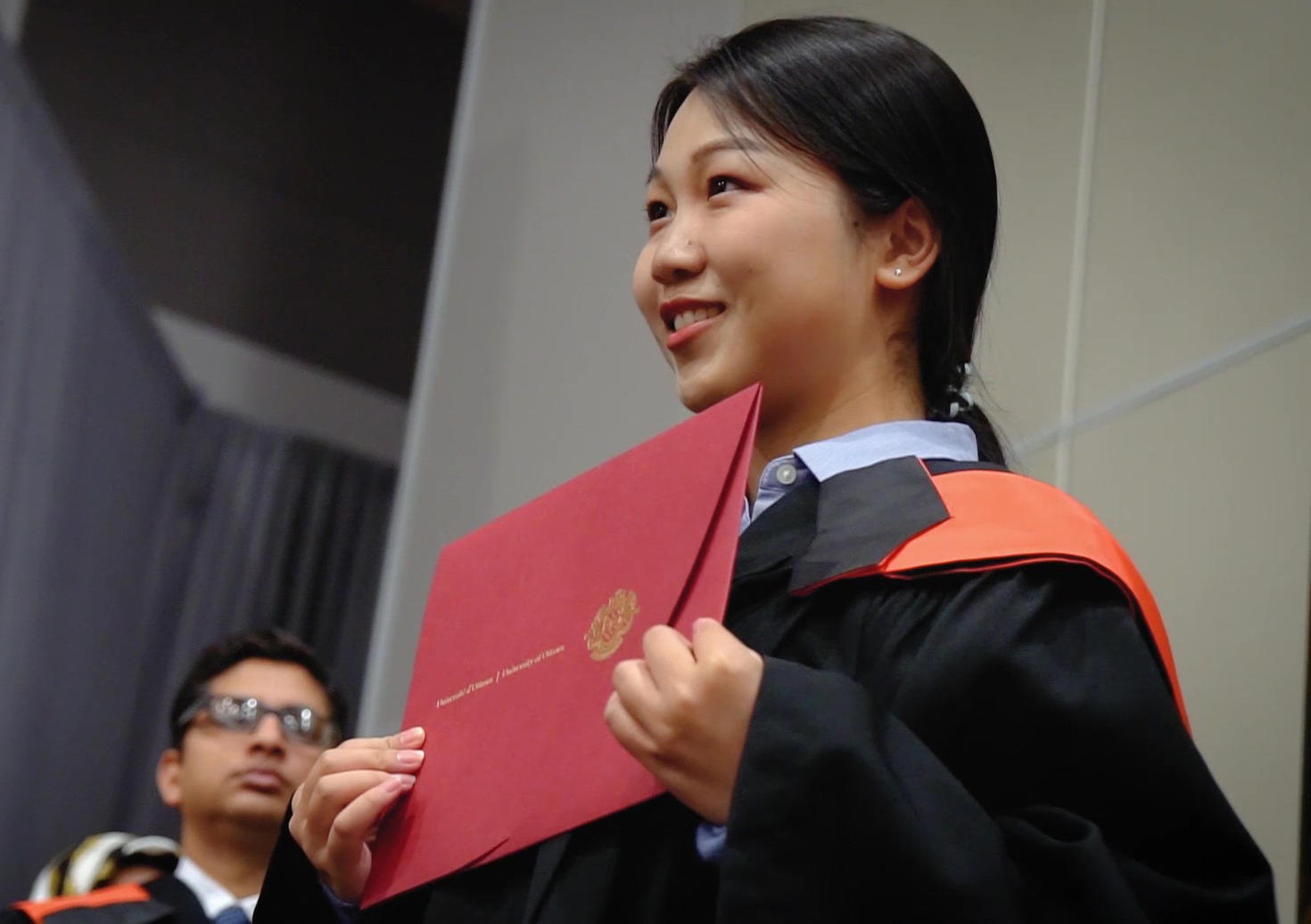 Student showing their diploma on stage at convocation.