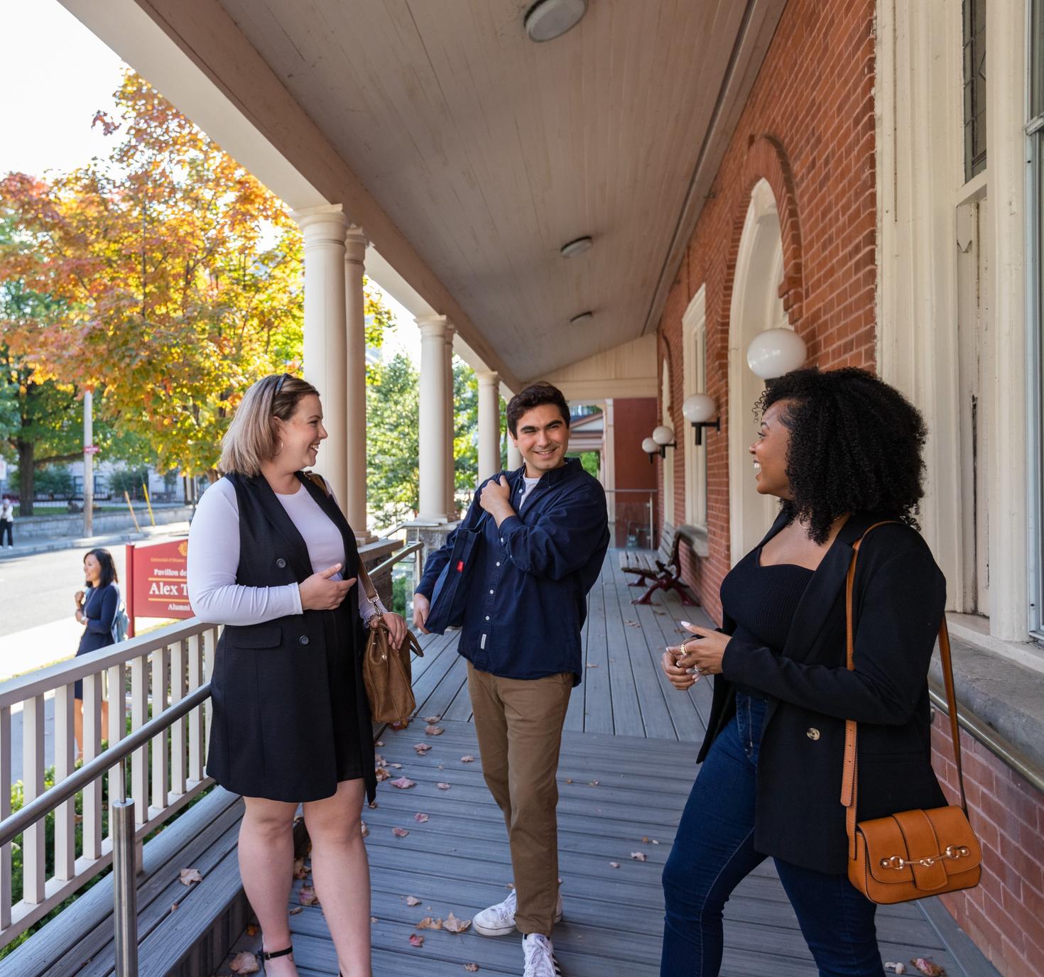 uOttawa alumni chatting outside on porch of Alumni Hall.