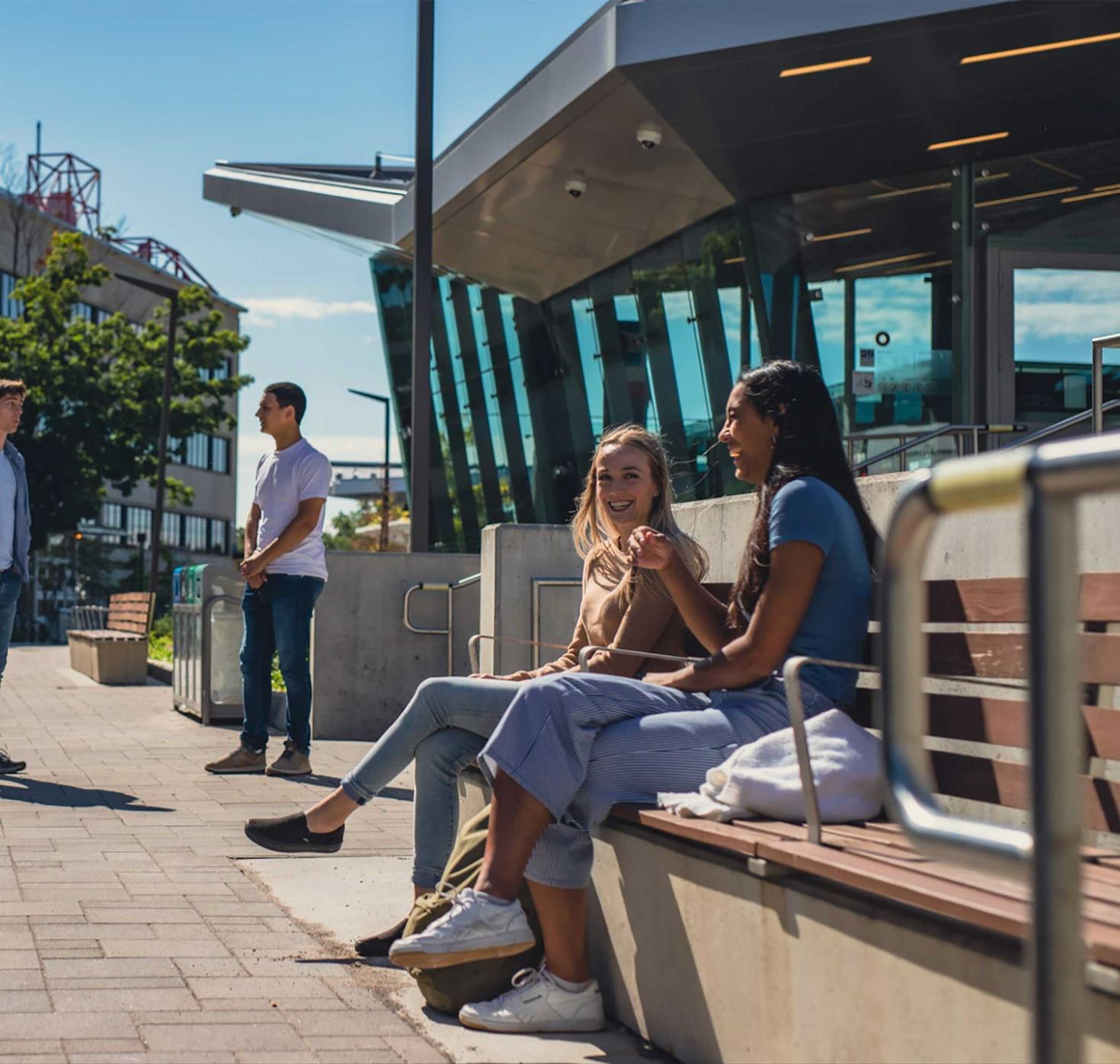 Students sitting outside of transit station talking.