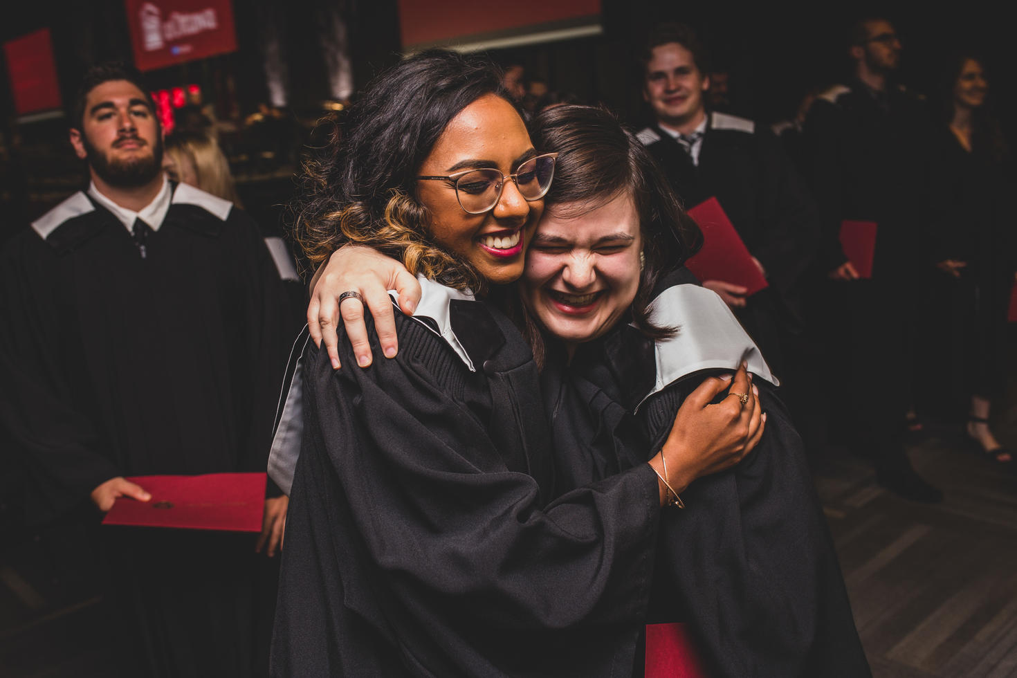 Two students hug and smile at convocation