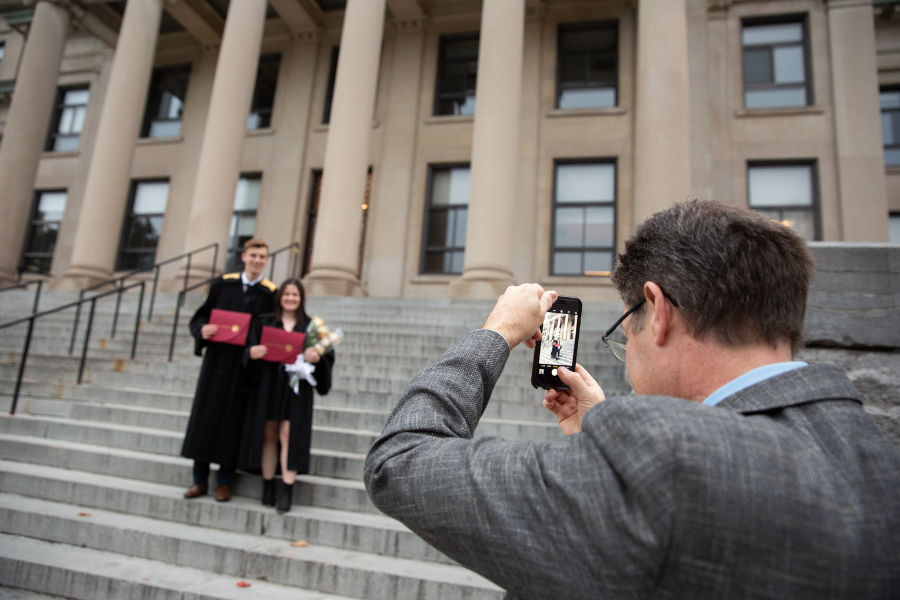 Person taking a photo of graduates at Tabaret Hall. 