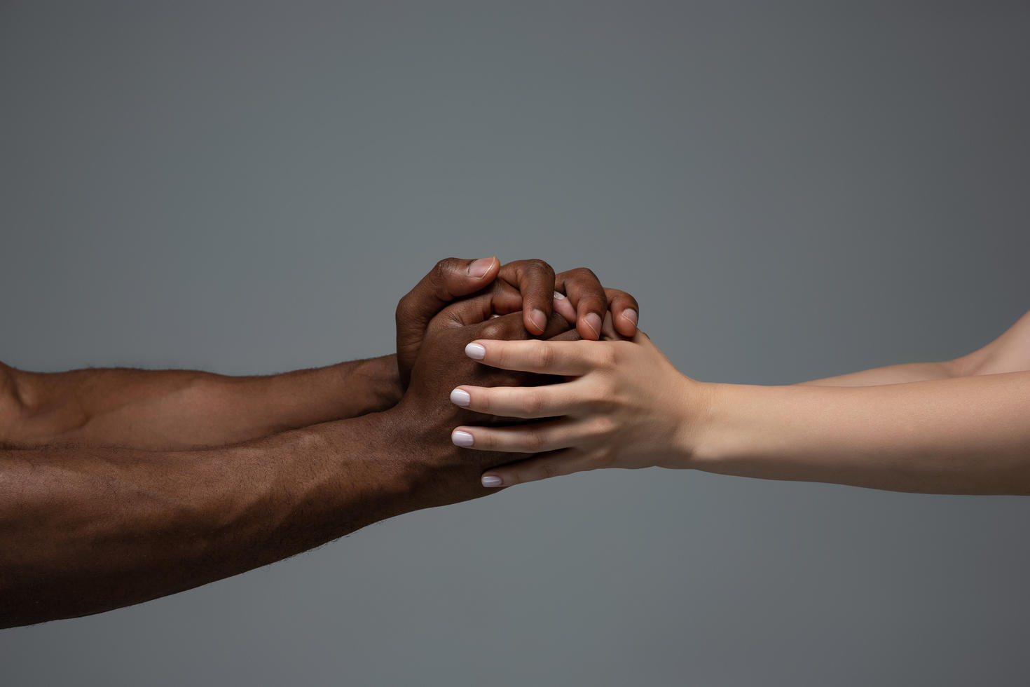 Des mains africaines et caucasiennes se tiennent.