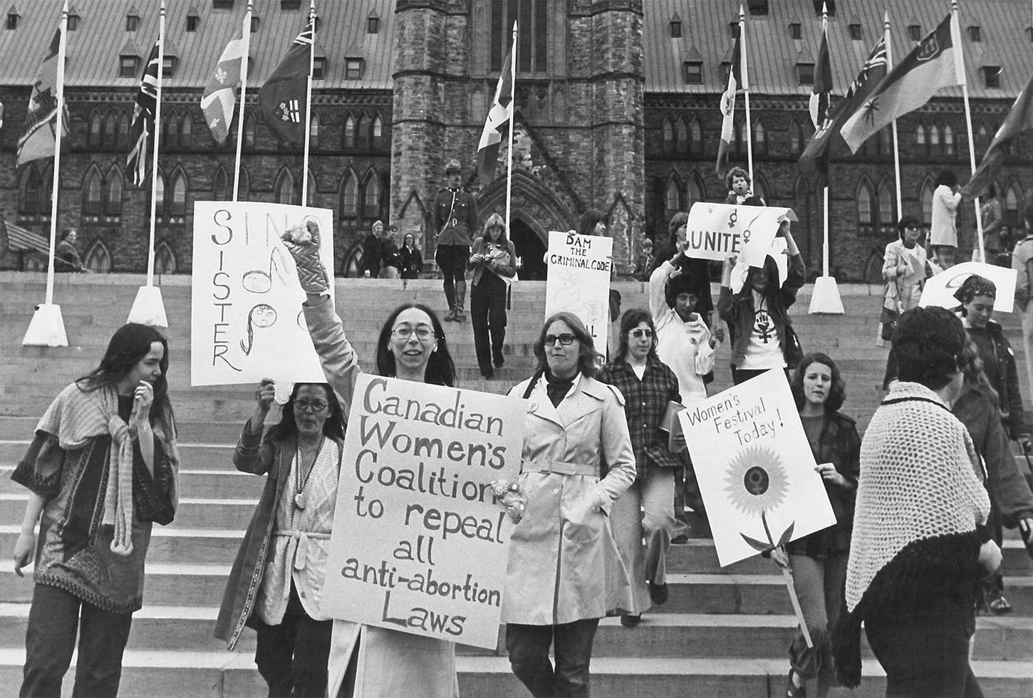 Des femmes manifestent devant la  Colline du Parlement avec des pancartes sur lesquelles on peut lire “Sin[g] Sister, Canadian Women's Coalition to repeal all anti-abortion Laws”, “Dam the Criminal Code” et “Women's Festival Today!”, Ottawa, [197?]. Photographe inconnu. Crédit: Archives et collections spéciales uOttawa.   