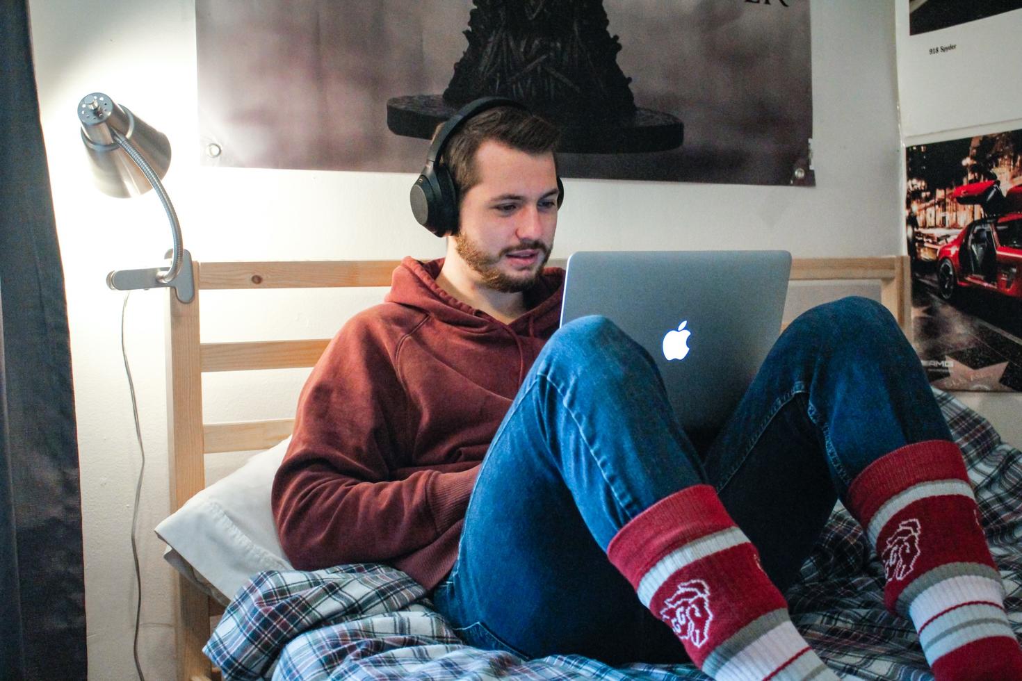 Person laying looking at a computer with headphones on.