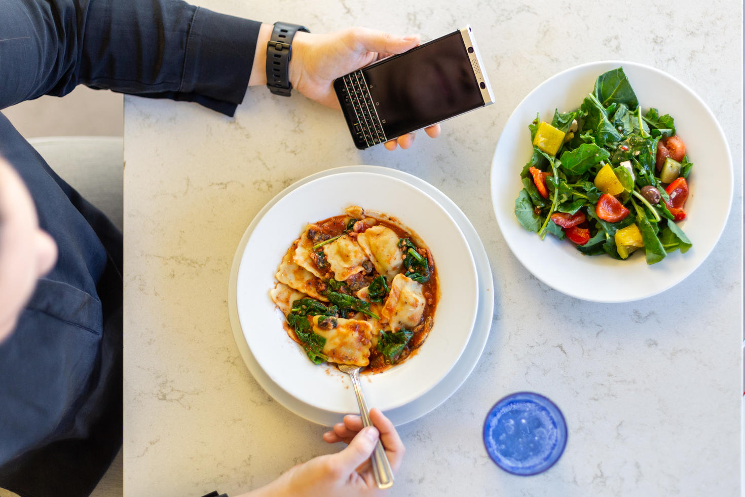 A person looking at their phone while eating a meal
