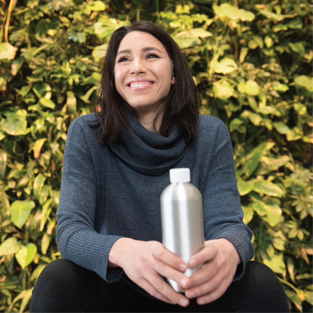 Celeste DiGiovanni, a student and founder of the H2Ottawa project holds her water bottle in front of the living wall in the FSS building