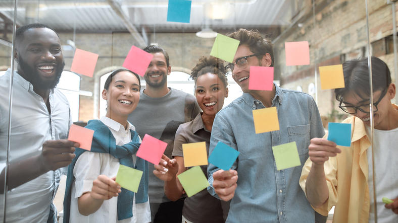 people putting sticky notes on wall